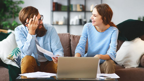 married couple with bills receipts documents and laptop at home