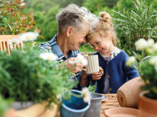 Senior grandmother with small granddaughter gardening on balcony in summer, resting.