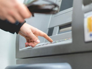 persons hand insert card in cash dispenser