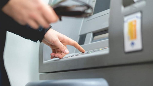persons hand insert card in cash dispenser
