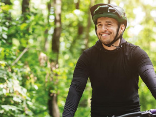 Joyful male bicyclist cycling in mountain forest