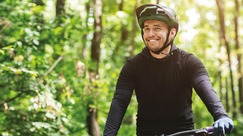 Joyful male bicyclist cycling in mountain forest