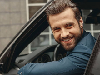 Laughing Caucasian business man in suit looking away in salon of automobile