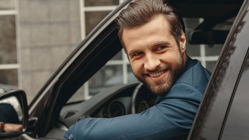 Laughing Caucasian business man in suit looking away in salon of automobile