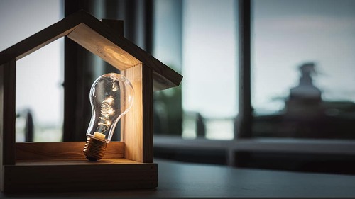 Light bulb with wood house on the table, a symbol for constructi
