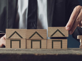 Realtor building houses of wooden blocks