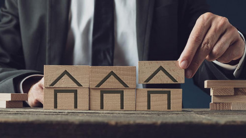 Realtor building houses of wooden blocks