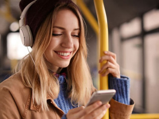 Young woman with headphones listening to music in public transpo