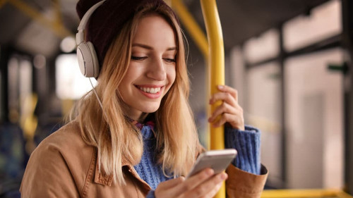 Young woman with headphones listening to music in public transpo