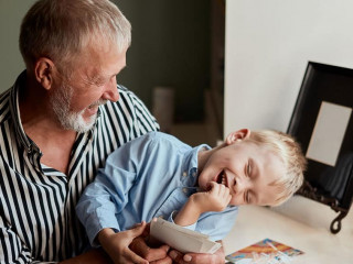 Grandfather and grandson on sofa at home. Grandpa and children watching old photos
