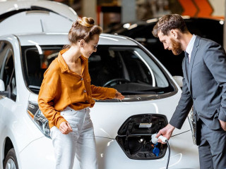 Sales manager with client near electric car at the car dealership