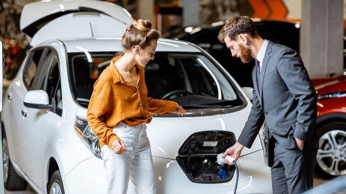 Sales manager with client near electric car at the car dealership