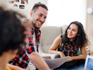 A group of young friends with laptop indoors, house sharing concept.