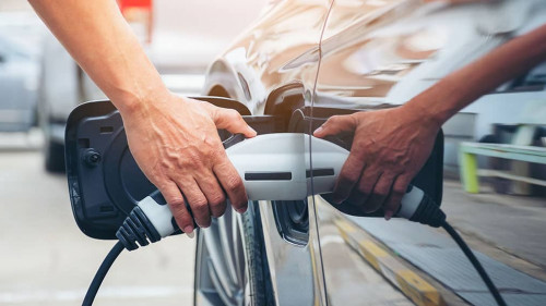 Hand hold of charging modern electric car battery on the street