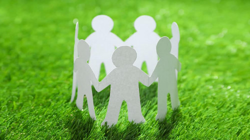 Paper people chain making circle on green grass. Unity concept