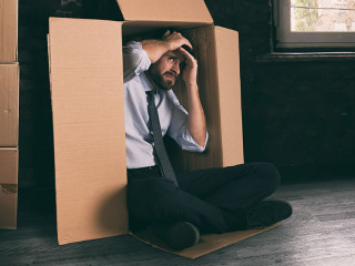 Businessman depressed for the failure of the company hidden in a cardboard box