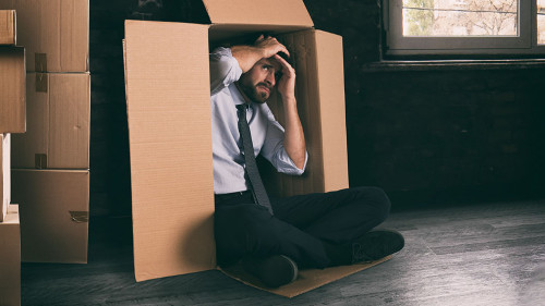 Businessman depressed for the failure of the company hidden in a cardboard box