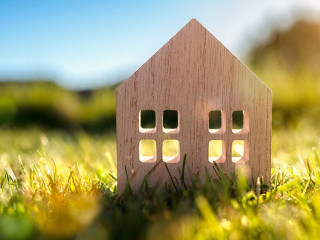 Ecological wood model house in empty field at sunset
