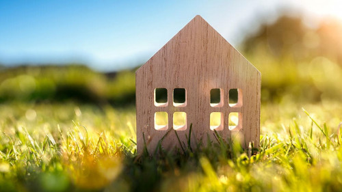 Ecological wood model house in empty field at sunset