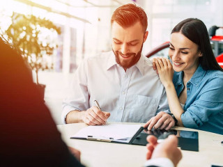 Happy couple with dealer buying car and signing documents in aut
