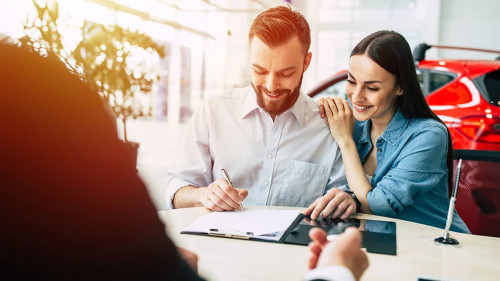 Happy couple with dealer buying car and signing documents in aut
