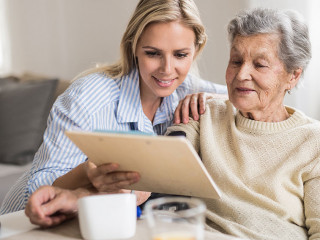 A health visitor measuring a blood pressure of a senior woman at home.