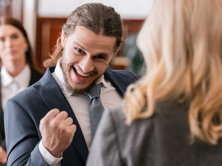 selective focus of excited businessman showing win gesture near advocate and prosecutor in court