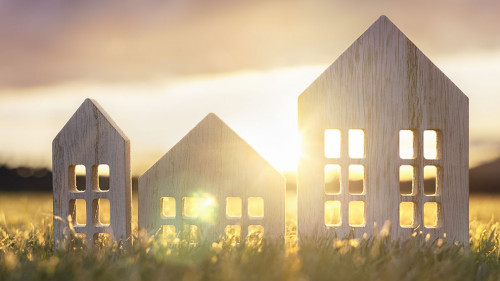 Ecological wood model house in empty field at sunset