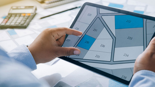 Man holding a tablet looking at lots of lands. Land plot managem