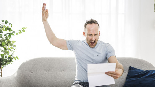 Shocked man holding some documents on sofa livingroom