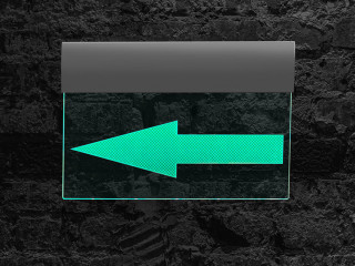 Luminous sign with bright green arrow to left against black, dar