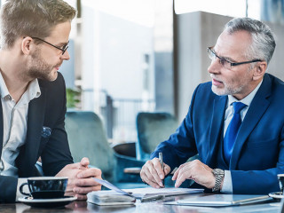 Horizontal shot of young executive showing his business proposal to a senior man sitting in foyer