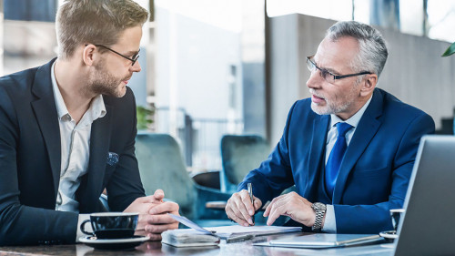 Horizontal shot of young executive showing his business proposal to a senior man sitting in foyer