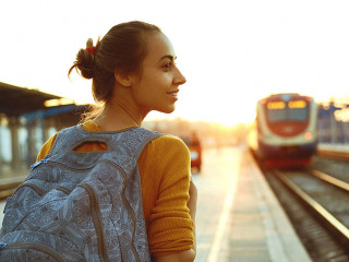 portrait of a young woman traveler with small backpack on the railway stantion