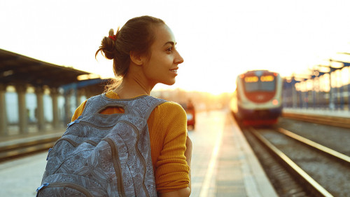 portrait of a young woman traveler with small backpack on the railway stantion