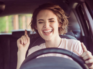 Photo of positive cheerful girl ride drive car town route wait traffic jam listen music sound try dance feel excited