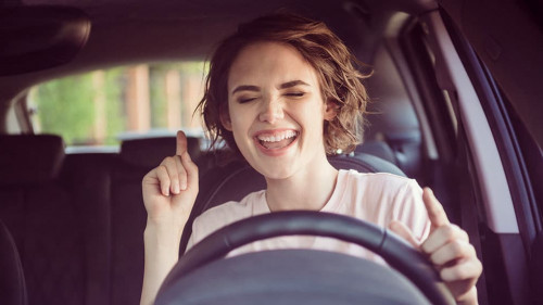 Photo of positive cheerful girl ride drive car town route wait traffic jam listen music sound try dance feel excited