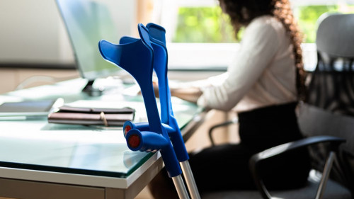 Kruecken-Frau-Office-441728412-AS-Andrey-Popov