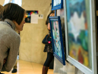 rear view of younga caucasian woman stading in an art gallery in front of two large colorful paintings