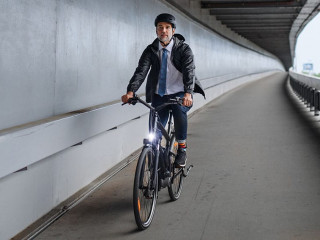 Businessman commuter on the way to work, riding bike over bridge, sustainable lifestyle concept.