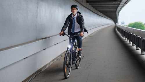 Businessman commuter on the way to work, riding bike over bridge, sustainable lifestyle concept.