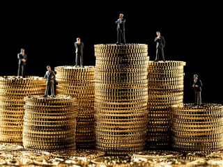 高く積み重ねたコインの上にミニチュアのビジ