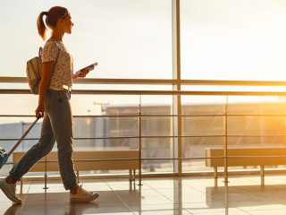 young woman goes  at airport at window with suitcase waiting for plane