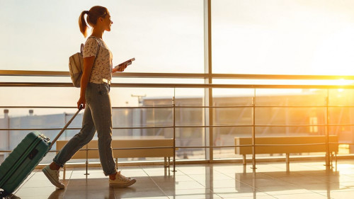 young woman goes at airport at window with suitcase waiting for plane