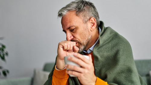 Allergic sick senior man coughing with a sore throat, holding a