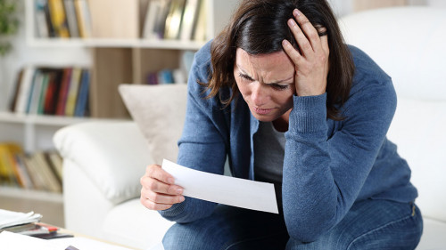 Sad adult woman checking receipts at home