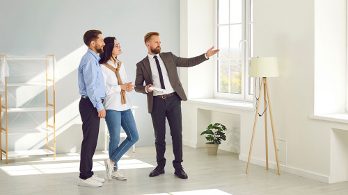 Real estate agent young man showing new big modern flat to couple of buyers or tenants.
