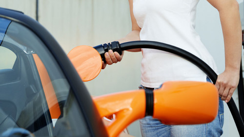 Pretty woman is loading electrically powered car outdoors