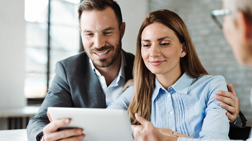 Happy couple using digital tablet on a meeting with insurance ag