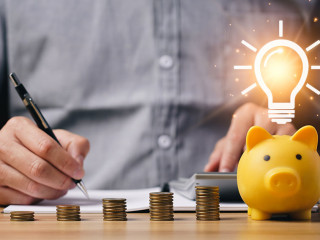 money and energy saving concept. businessman calculates savings on a table with a notebook and a piggy bank with light bulb icon. family provident fund family provident fund